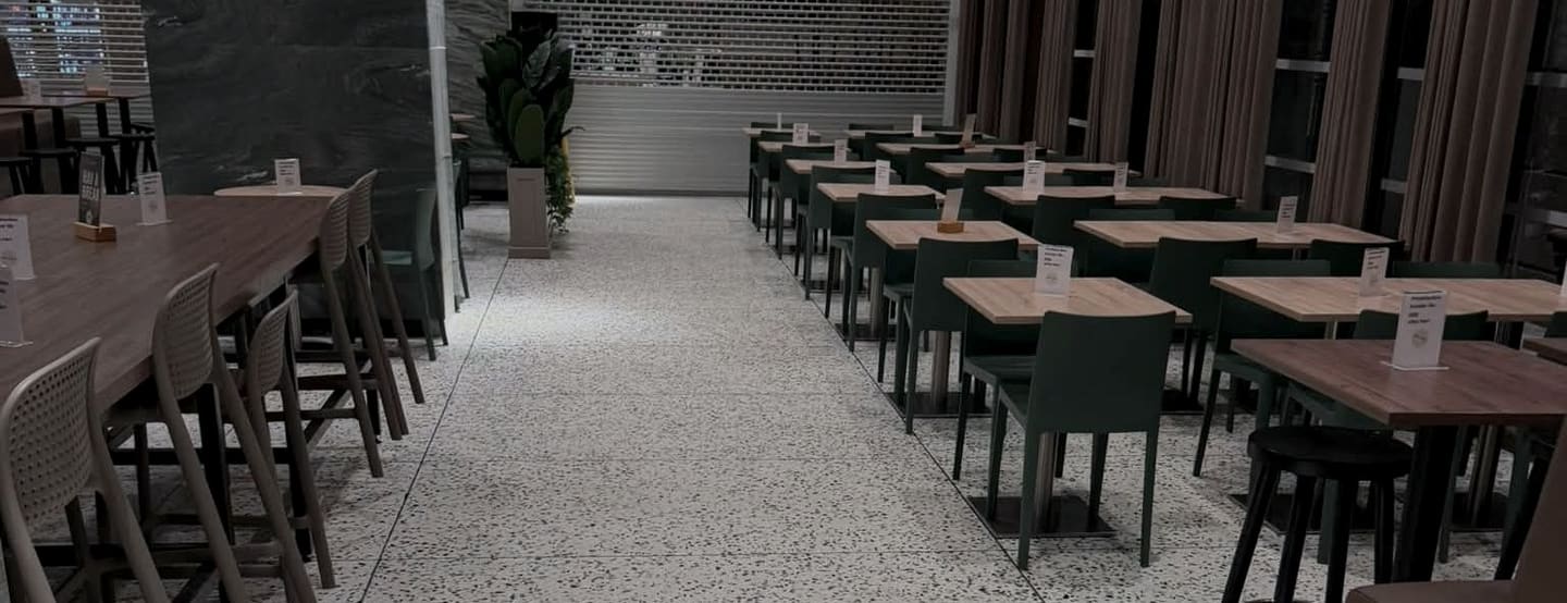 Matsal med rader av bord på ett ljust terrazzogolv med svarta stenkorn – ett av våra uppdrag